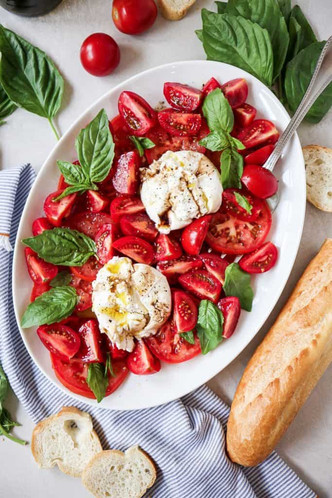 burrata caprese salad with heirloom Tomatoes with creamy burrata cheese fresh Basil, olive oil, and French baguette 