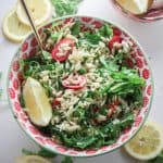 pasta salad with freshly squeezed lemon juice and herbs in a red bowl with fresh basil and lemon