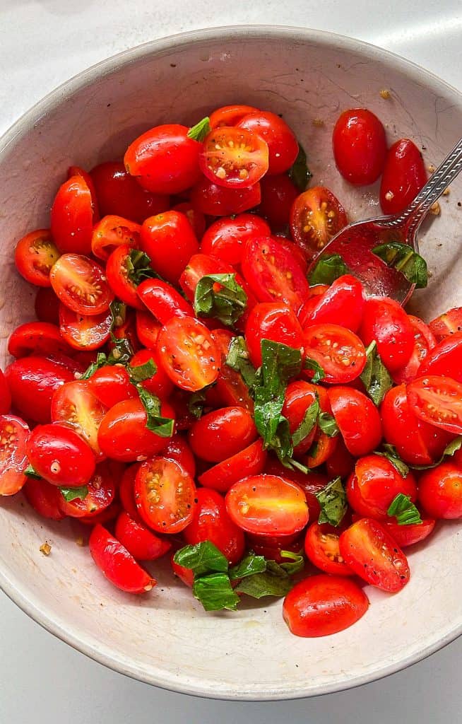 bowl of marinated cherry tomatoes with olive oil, garlic, fresh basil, salt, pepper, and red wine vinegar
