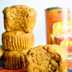healthy zucchini pumpkin muffins stacked next to a can of pumpkin puree