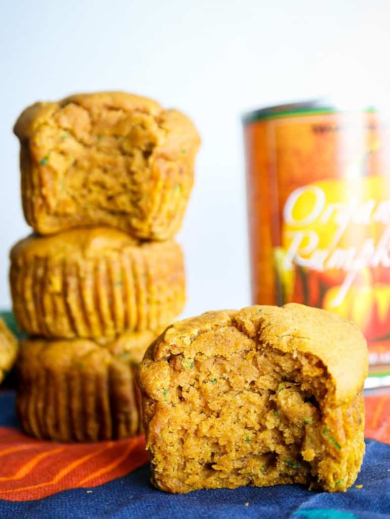 healthy zucchini pumpkin muffins stacked next to a can of pumpkin puree