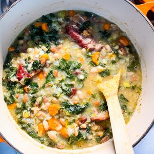 Pot of ham and white bean kale soup in an orange dutch oven on the stove