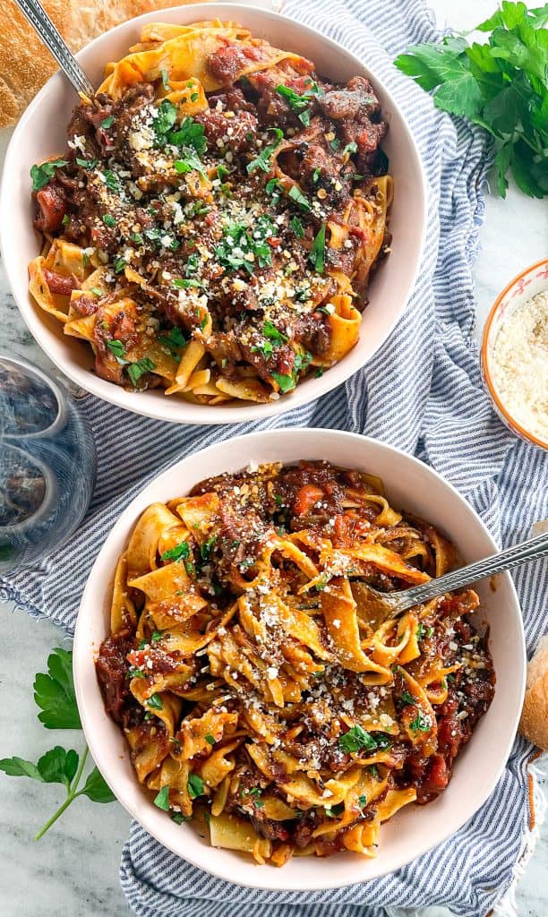 slowly braised Short Rib Ragu recipe over pappardelle in bowls with parmesan and parsley