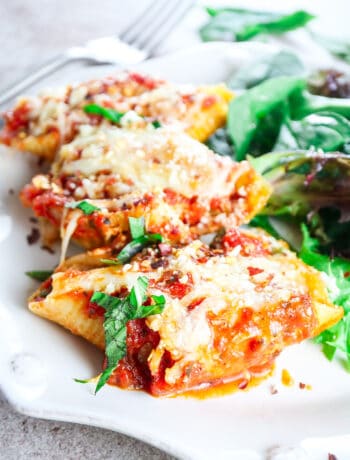 giant stuffed shells with ricotta and zucchini topped with marinara and mozzarella and garnished with fresh basil