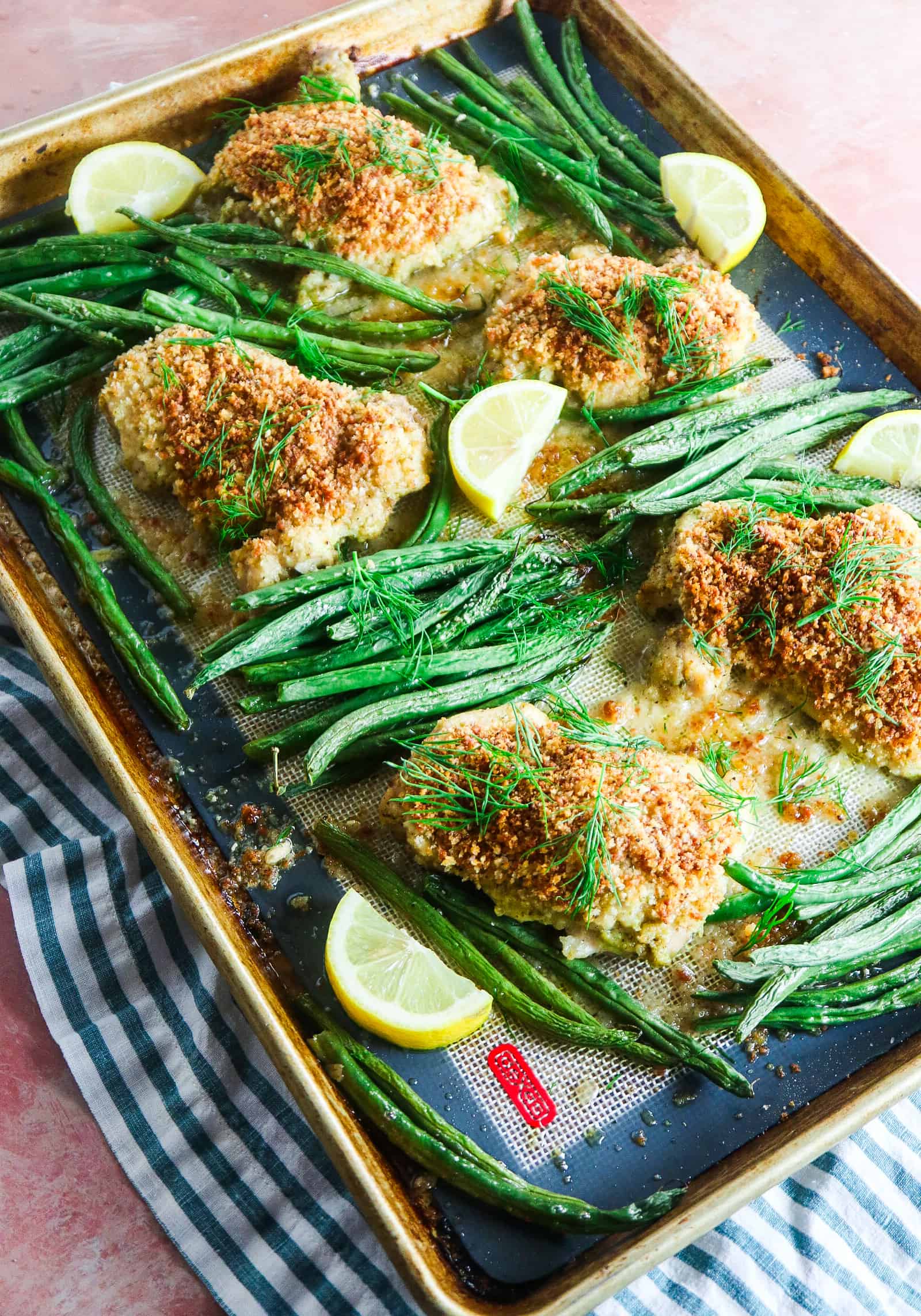 crispy panko chicken with green beans on a sheet pan with fresh dill and lemon