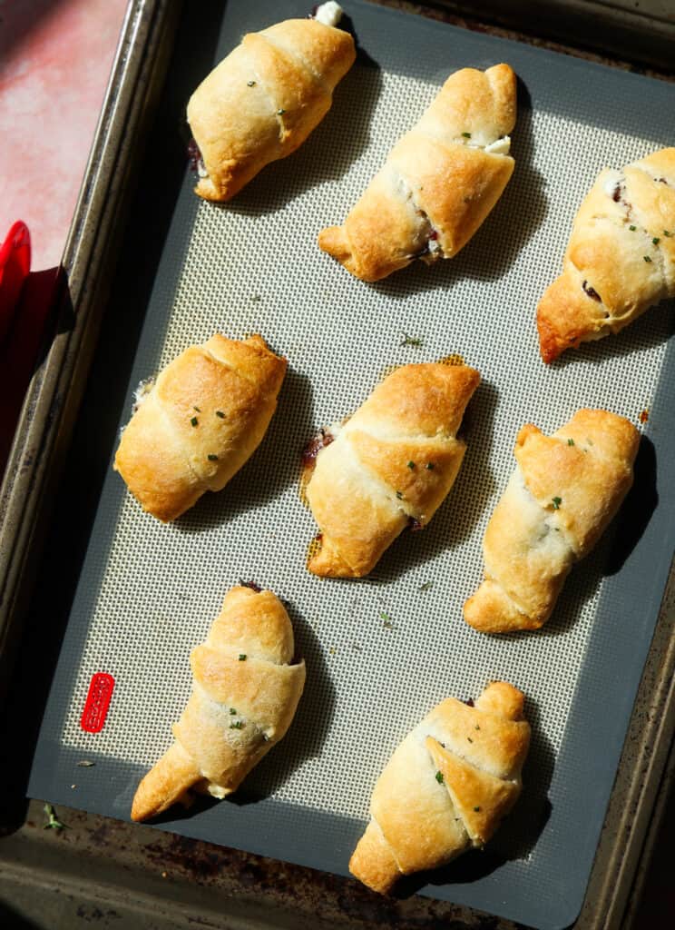 cranberry goat cheese filled crescent rolls with thyme and honey on a sheet pan