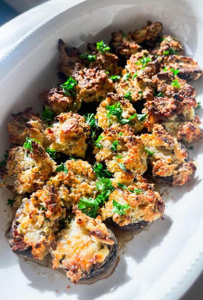 bacon and Boursin stuffed mushrooms in a white casserole dish with fresh parsley 