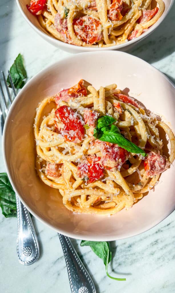 creamy Boursin tomato pasta with fresh basil and parmesan in pink bowls