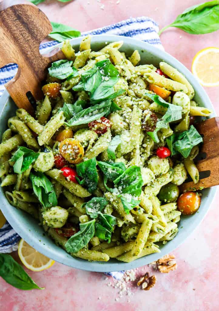 pesto caprese penne pasta in a big bowl topped with basil and parmesan