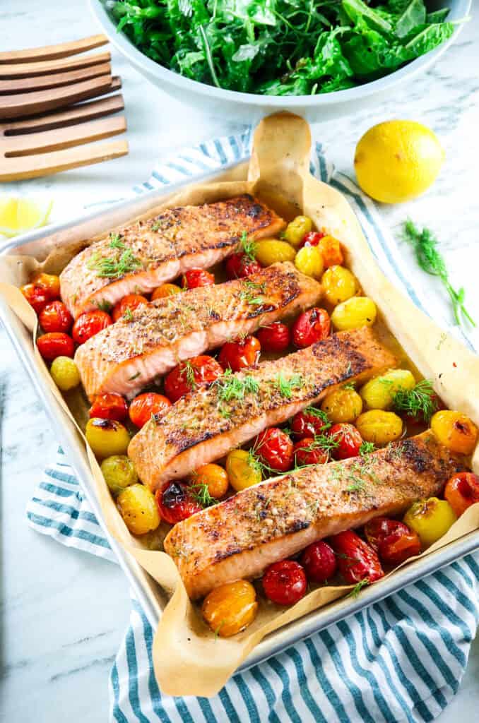 sheet pan salmon with cherry tomatoes and fresh dill with mixed greens and lemon 