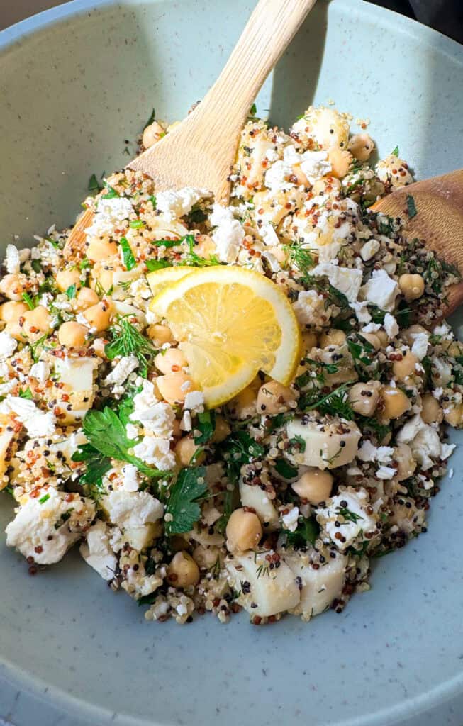 chickpea salad with quinoa and feta in a sage green bowl with fresh herbs and lemon 