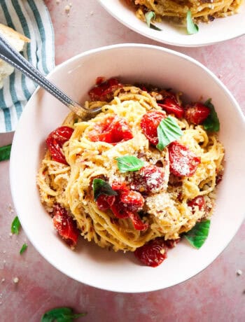 spicy roasted angel hair pasta with fresh tomatoes and basil in pink bowls with grated parmesan