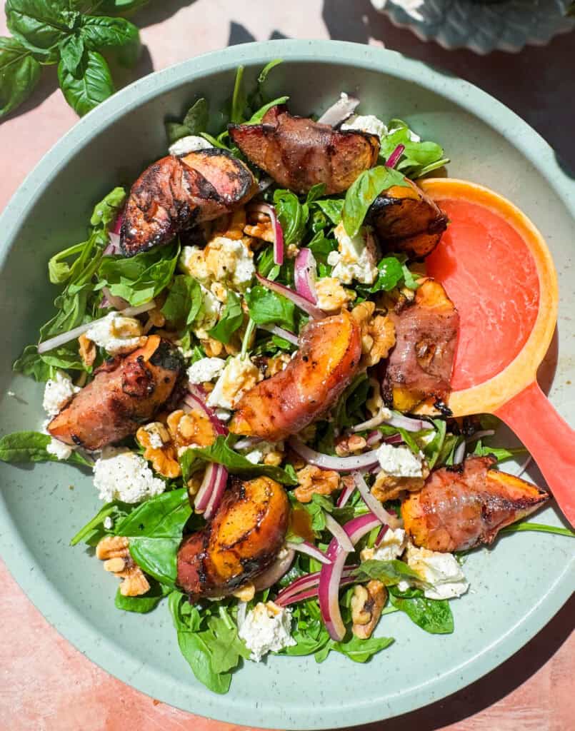 grilled peaches wrapped in proscuitto served on a bed of arugula with red onion, goat cheese, walnuts, and a honey balsamic vinaigrette