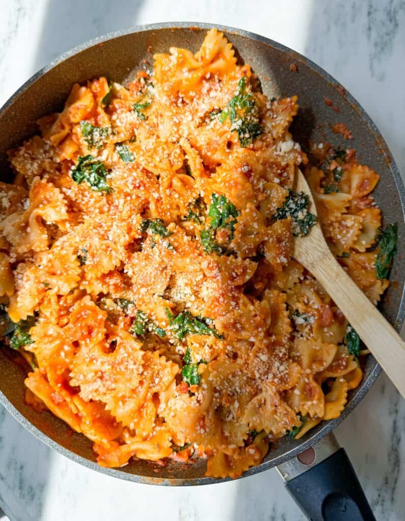 the easiest fall pasta using all trader joes ingredients-farfalle pasta, pancetta, shallots, autumnal harvest pasta sauce, and kale.